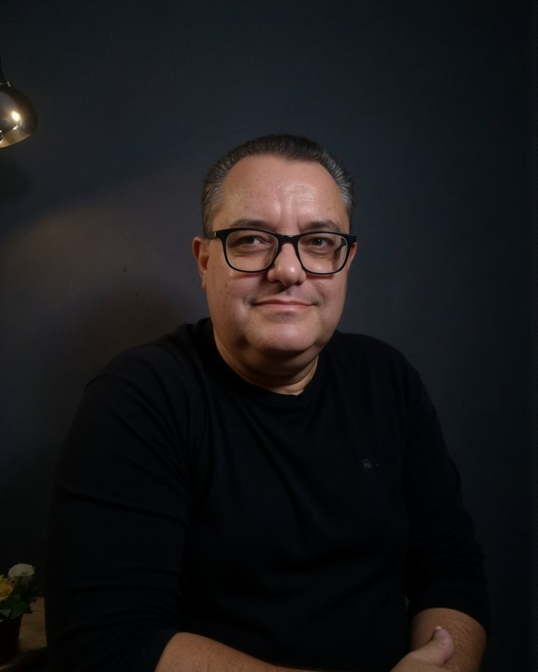 Alexandre Fortuna, de óculos e blusa preta, com os braços cruzados e um leve sorriso